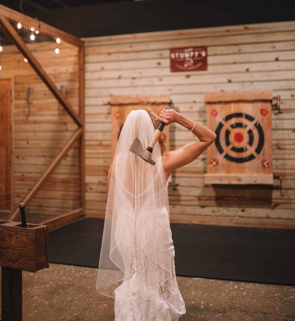 Bride in wedding dress throwing axe at a bullseye